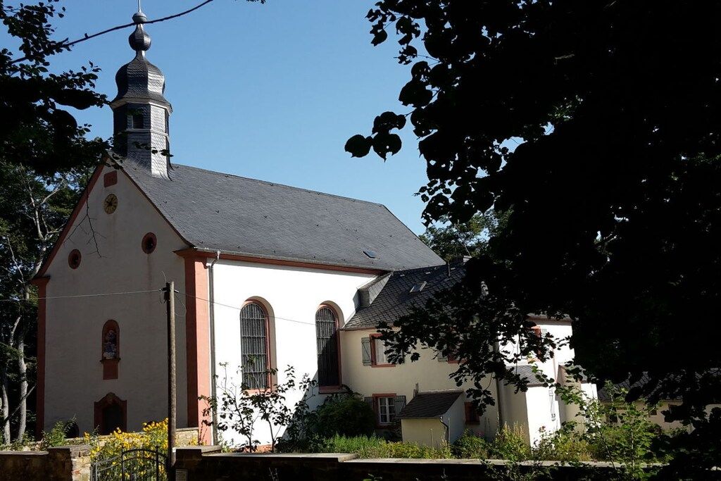 Une église dotée d’un clocher, de fenêtres en arc de cercle et d’un petit bâtiment attenant.