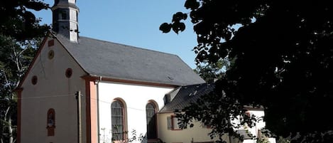 Une église dotée d’un clocher, de fenêtres en arc de cercle et d’un petit bâtiment attenant.