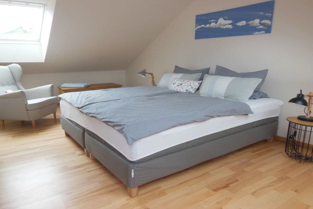Un dormitorio con una cama, una silla, una mesita de noche y una lámpara.