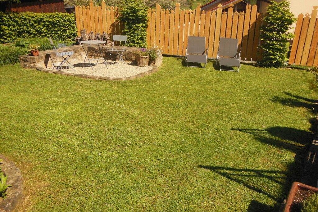 Un jardin avec un espace de détente circulaire, une clôture en bois et une pelouse verdoyante.