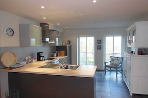 A modern kitchen with a central island, built-in appliances, and a dining area with a chair. - Holiday apartment with 2 bedrooms (Holsthum)