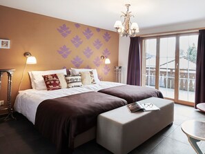A hotel room with a large bed, two bedside lamps, a chandelier, and a view of the outdoors through a large window. - Haus Rätia App 16 Appartement/Fewo, Dusche oder Bad, WC 2½-Zimmerwohnung by Interhome (Klosters)