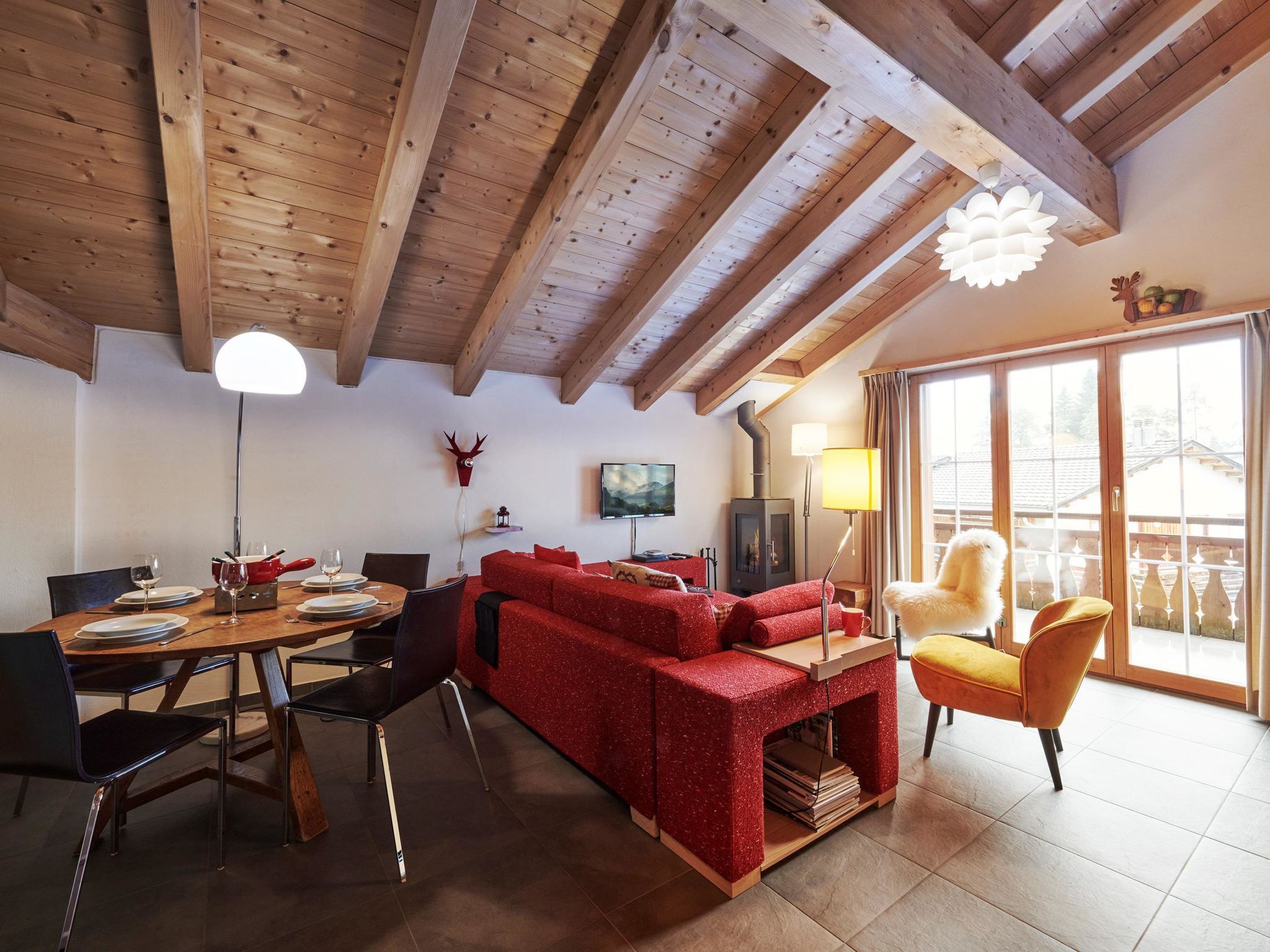 Un salon chaleureux avec un canapé rouge, une table à manger en bois et une cheminée.