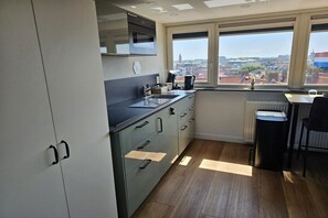 A modern kitchen with a view of the city, featuring a microwave, sink, and cabinets. - Holiday apartment with 1 bedroom (Zandvoort)