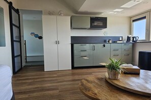 Una cocina moderna con microondas, horno y cafetera. Hay una mesa de comedor de madera con una planta encima.