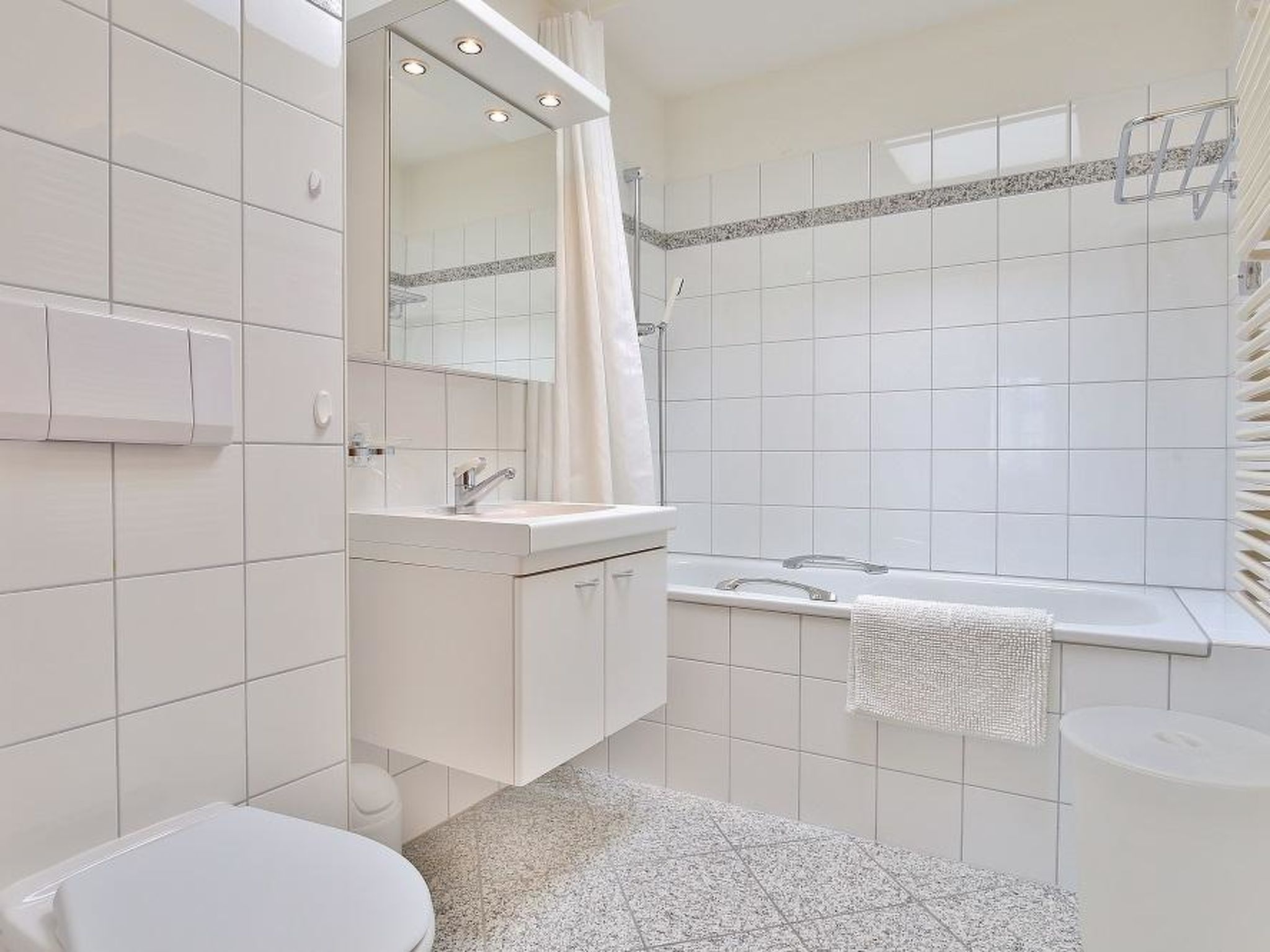 Une salle de bain moderne équipée de toilettes, d’un lavabo, d’un miroir et d’une douche.