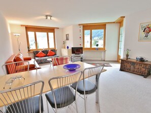 A modern living room with a dining area, large windows, and a view of the outdoors. - Auf der Matta C22 Appartement/Fewo, Dusche oder Bad, WC 3-Zimmerwohnung by Interhome (Davos)