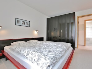 A modern bedroom with a large bed, a bedside table, a framed picture on the wall, and a wardrobe with a mirror. - Auf der Matta C22 Appartement/Fewo, Dusche oder Bad, WC 3-Zimmerwohnung by Interhome (Davos)