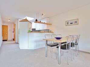 A modern kitchen with a central island, a dining area with a table and chairs, and a hallway leading to a door. - Auf der Matta C22 Appartement/Fewo, Dusche oder Bad, WC 3-Zimmerwohnung by Interhome (Davos)