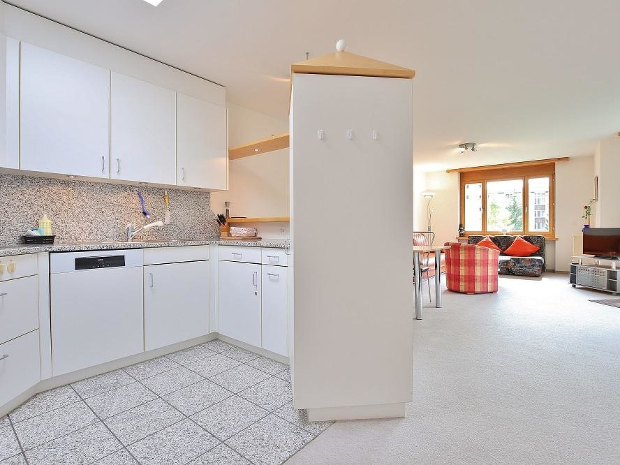 A modern kitchen with white cabinets, a built-in dishwasher, and a large refrigerator.