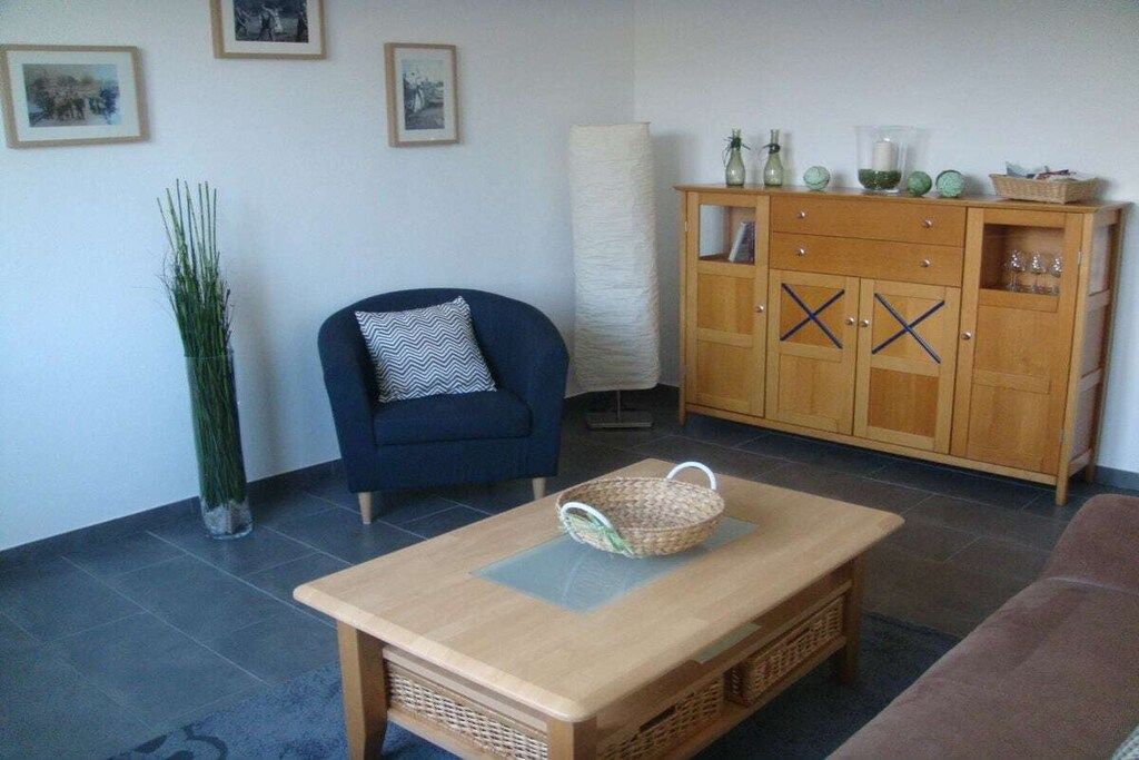 Una sala de estar con un sofá, una mesa de centro, un aparador y una planta alta.