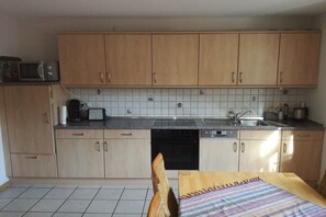 A compact kitchen with wooden cabinets, a microwave, a toaster, and a sink. - Holiday apartment in Plein with barbecue (Plein)