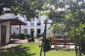 A courtyard with a covered seating area, a small building with a door, and a bench. - Holiday apartment in Plein with barbecue (Plein)