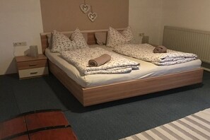 A double bed with a wooden frame, two nightstands, a wall-mounted heater, and heart-shaped decorations. - Holiday apartment with 1 bedroom (Oberhausen)