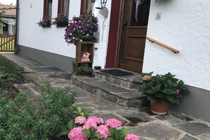 A white building with a wooden door, stone steps, and potted plants. - Holiday apartment with 1 bedroom (Oberhausen)