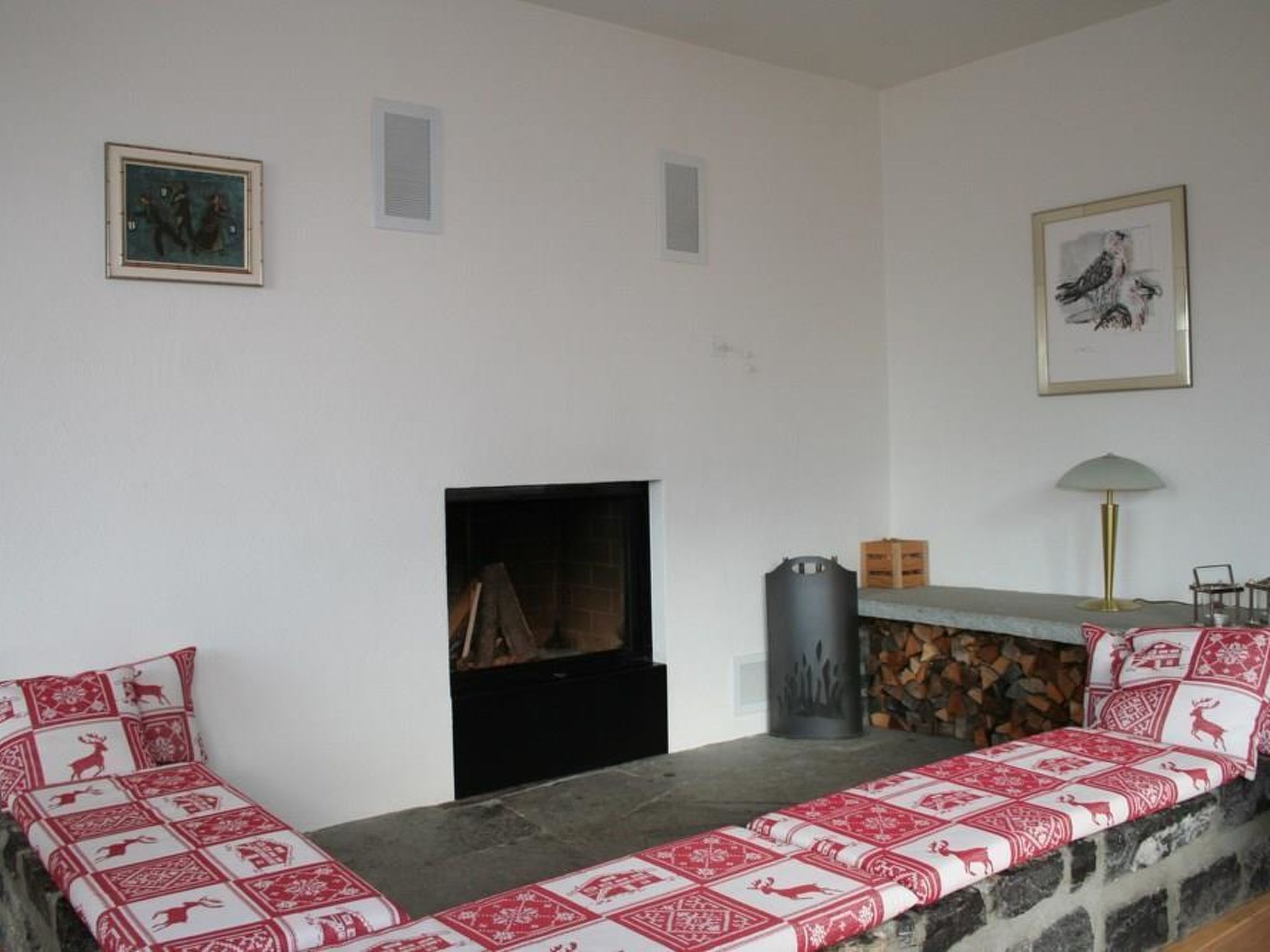 Ein Wohnzimmer mit Kamin, einer Steinsitzbank und zwei gerahmten Bildern an der Wand.