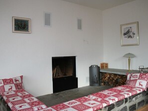Ein Wohnzimmer mit Kamin, einer Steinsitzbank und zwei gerahmten Bildern an der Wand.