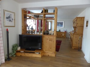 Ein Unterhaltungsschrank aus Holz mit einem Flachbildfernseher, einem roten Vorhang und einer kleinen Pflanze.