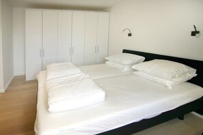 A bedroom with a large bed, a wardrobe, and a wall-mounted light fixture. - Beach Residence A305 (Cadzand)