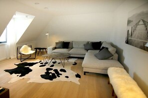 A modern living room with a sectional sofa, a round coffee table, a cowhide rug, and a chair. - Beach Residence A305 (Cadzand)