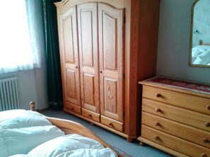 A bedroom with a bed, a wooden wardrobe, a dresser, and a mirror on the wall. - Hertisun 7 Appartement/Fewo, Dusche oder Bad, WC 2½-Zimmerwohnung by Interhome (Davos)