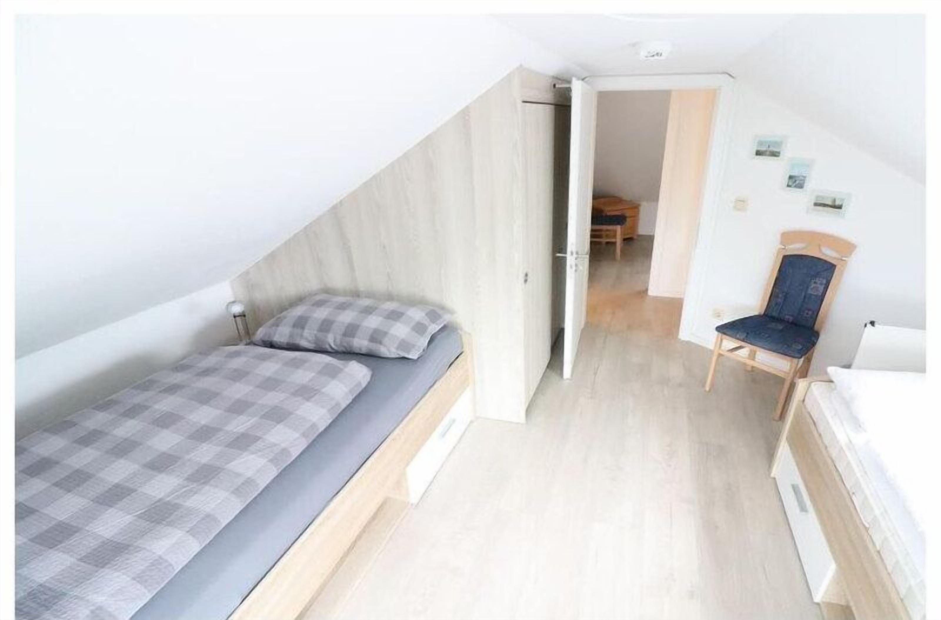 A bedroom with a bed, a chair, and a small table.