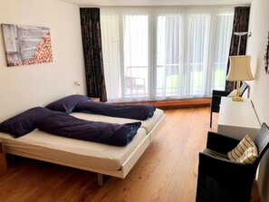 A room with two beds, a window with sheer curtains, a lamp, and a painting on the wall. - Saleza 104 Appartement/Fewo, Dusche oder Bad, WC 2-Zimmerwohnung by Interhome (Davos)