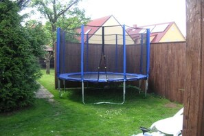 Ein Garten mit Trampolin, umgeben von einem blauen Sicherheitsnetz.
