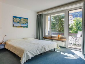 Ein Schlafzimmer mit Bett, Fenster, Schreibtisch und Stuhl.