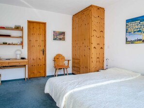 Ein Schlafzimmer mit Bett, Schreibtisch, Stuhl, Kleiderschrank und einem Bild an der Wand.