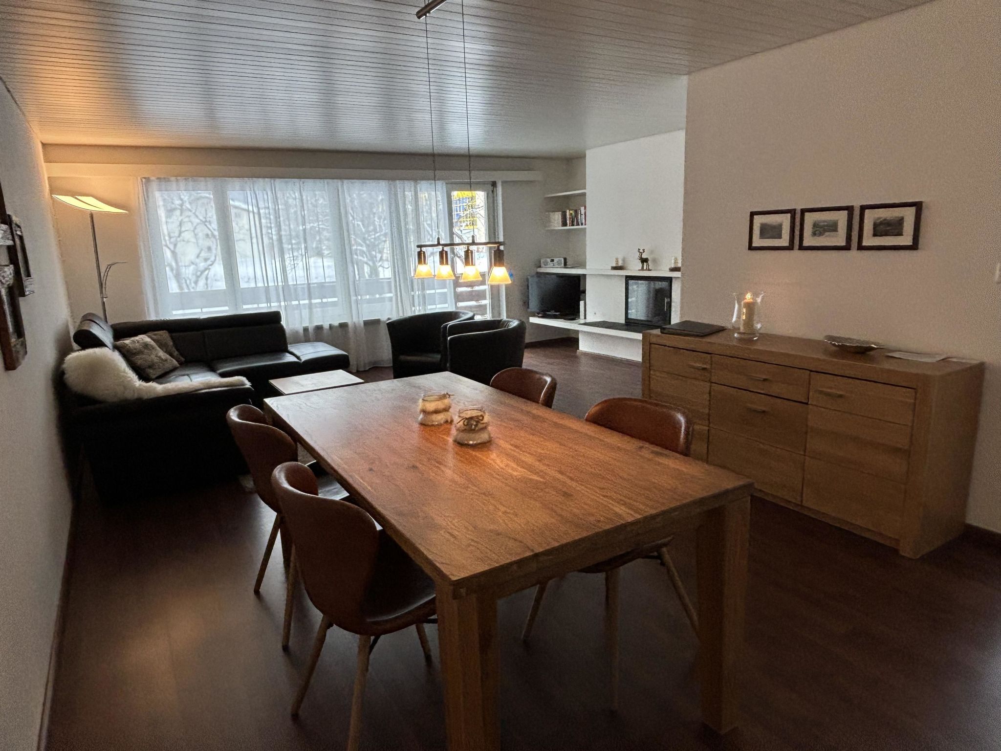 Un espacio moderno de estar con comedor, sofá y chimenea.