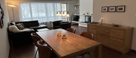 Un espacio moderno de estar con comedor, sofá y chimenea.