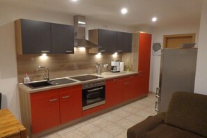 Cozinha compacta com pia dupla, fogão e forno, com armários modernos e iluminação sob os armários.