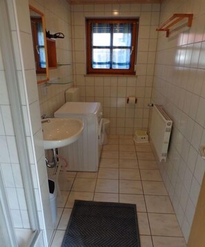 Ein kleines Badezimmer mit Waschbecken, Toilette und Fenster.