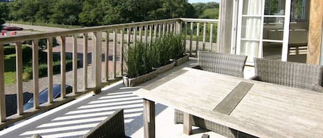 A balcony with wicker furniture, a view of the road, and a building in the background.