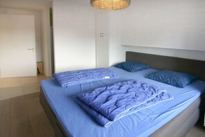 Ein Schlafzimmer mit einem Bett, Kissen, einem Kleiderschrank und einer Pendelleuchte.
