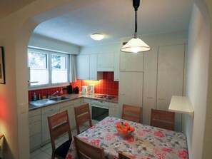 A compact kitchen with a dining table, chairs, and a hanging light fixture. - Casa Berger Appartement/Fewo, Dusche oder Bad, WC 3½-Zimmerwohnung by Interhome (Davos)