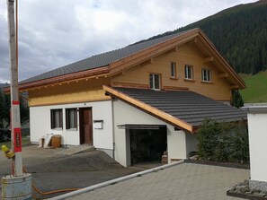 Ein zweigeschossiges Haus mit Garage, einem kleinen Anbau und einem gepflasterten Auffahrt.