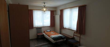 A compact room with a bed, a desk, a chair, and a sofa.