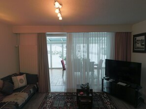 Sala de estar com sofá, televisão, mesa de centro e tapete estampado.