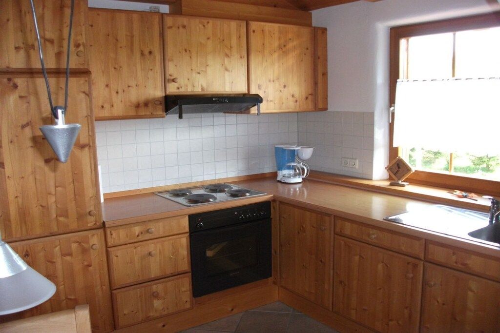 Une cuisine avec des meubles de rangement en bois, une cuisinière, un four et une fenêtre donnant sur un beau paysage.