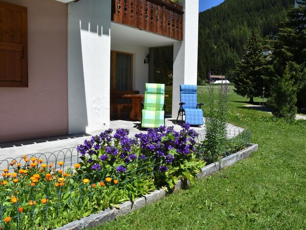 Uma casa com varanda, porta de madeira e jardim florido.