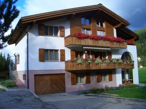 A two-story building with wooden balconies, a garage, and a well-maintained garden. - Sunna Büel Appartement/Fewo, Dusche oder Bad, WC 2½-Zimmerwohnung by Interhome (Davos)