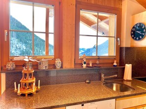 A kitchen with granite countertops, a sink, and a window with a view of a snowy mountain. - Sunni 2 Appartement/Fewo, Dusche oder Bad, WC 3-Zimmerwohnung by Interhome (Davos)