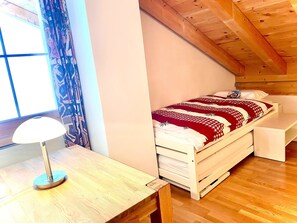 A bedroom with a wooden ceiling, a bed with a checkered blanket, a bedside table, and a lamp. - Sunni 2 Appartement/Fewo, Dusche oder Bad, WC 3-Zimmerwohnung by Interhome (Davos)