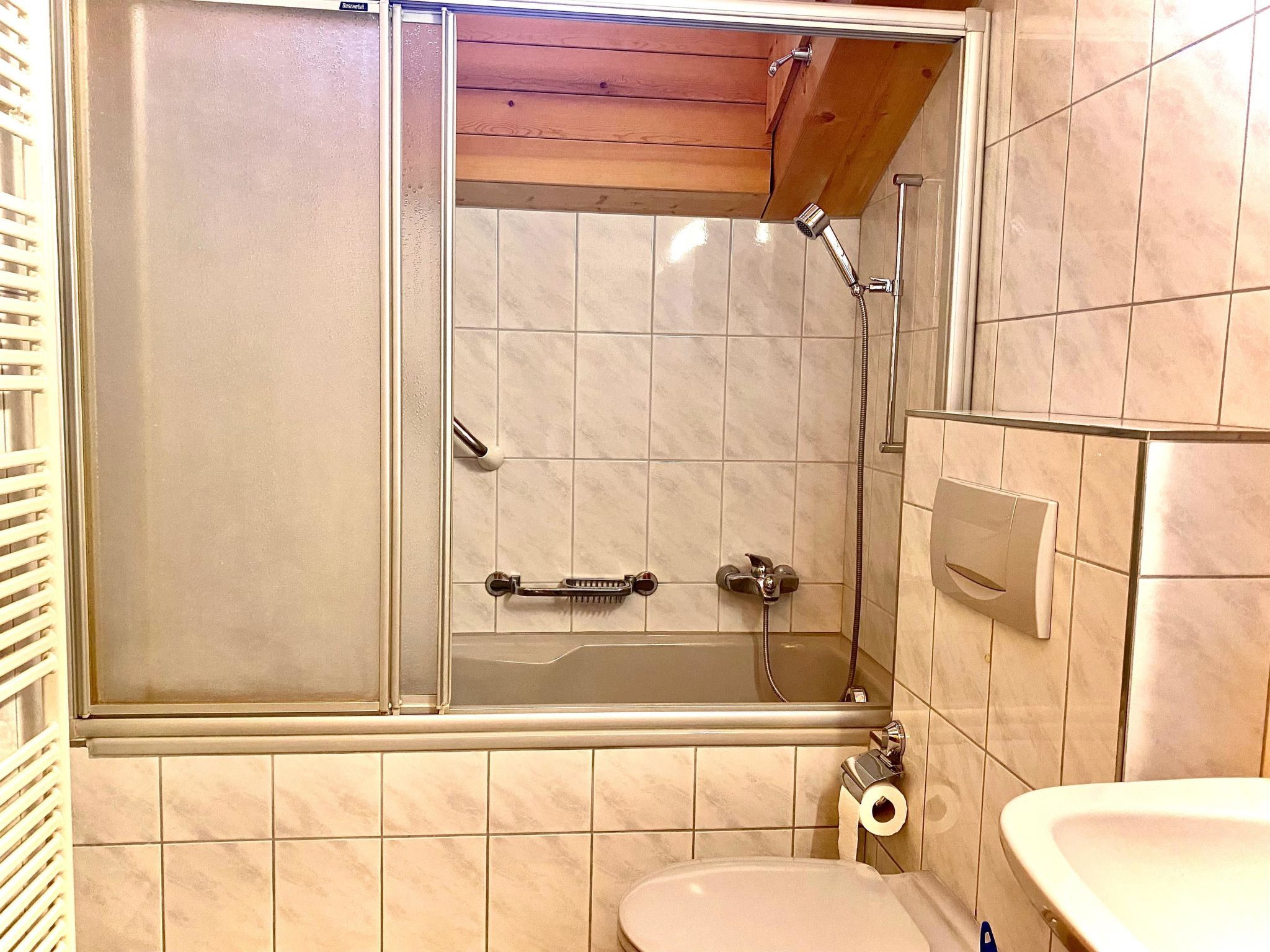 A bathroom with a shower enclosure, a toilet, and a sink.