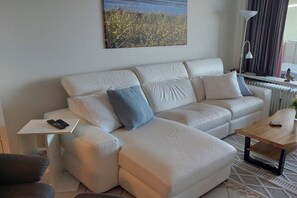 A modern living room with a sofa, a coffee table, and a side table with a phone. - Luca Panorama Apt. 74, 5th floor (Cuxhaven)