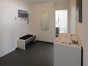 A small, clean room with a bench, a mirror, and a small table with papers. - Residenz im Park Whg Alpenblick Appartement/Fewo, Dusche oder Bad, WC by Interhome (Davos)