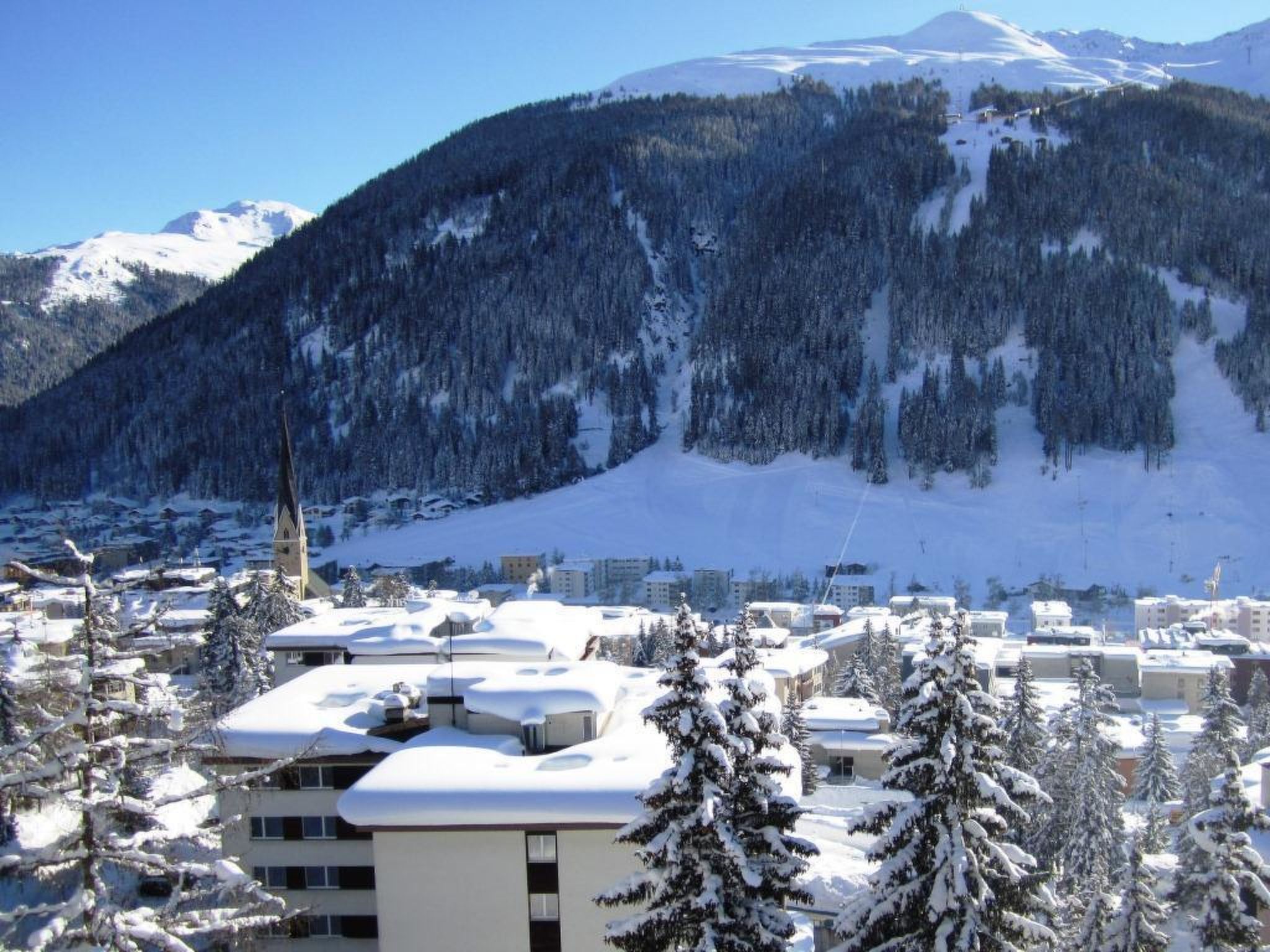 Eine verschneite Stadt mit Gebäuden und einem Berg im Hintergrund.