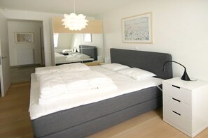 A modern bedroom with a bed, bedside table, and a mirror. - Beach Residence A302 (Cadzand)